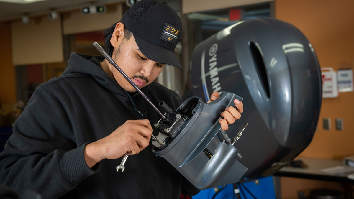 Marine services student working on an outboard engine