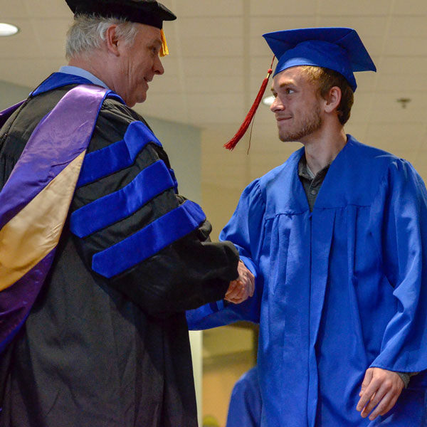 graduate at commencement ceremony shaking hands