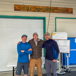 Three men smiling towards camera.