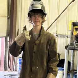 Boy with welding gear on doing a thumbs up. 