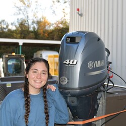 Girl beside a Yamaha outboard engine.
