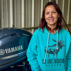 Woman smiling standing by outboard motor.