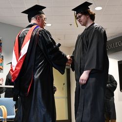student graduates from college and shaking hands with college director