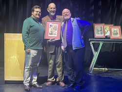 Three men on a stage with an award.