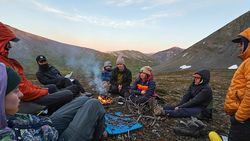 Group of people outside sitting around a fire.