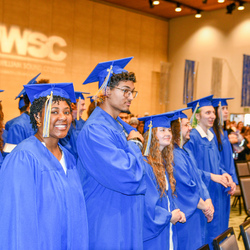 Student smiling at her commencement and several other students are in photo. 
