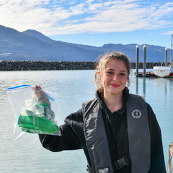 Student holding up a instructment in a bag.