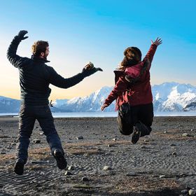 College students jumping for joy on a beach in Valdez, Alaska