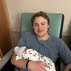 Man holding a swaddled baby. 