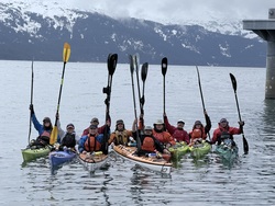 People in kayaks on the ocean.