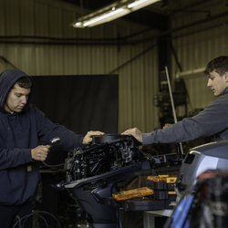 Two students working on an outboard motor. 