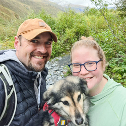 Man and woman with dog smiling. 