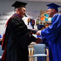 man graduating shaking hands with another man