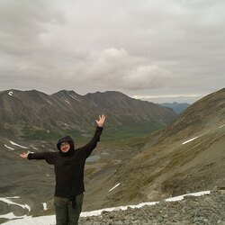 Man on mountain with arms outstretched. 
